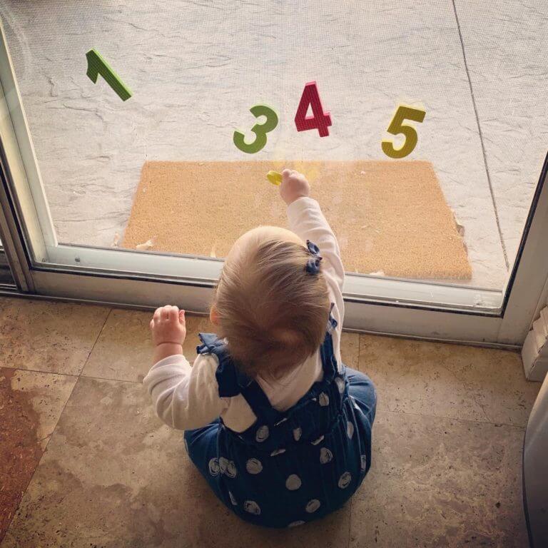 Baby learning numbers by playing with sponges stuck to window