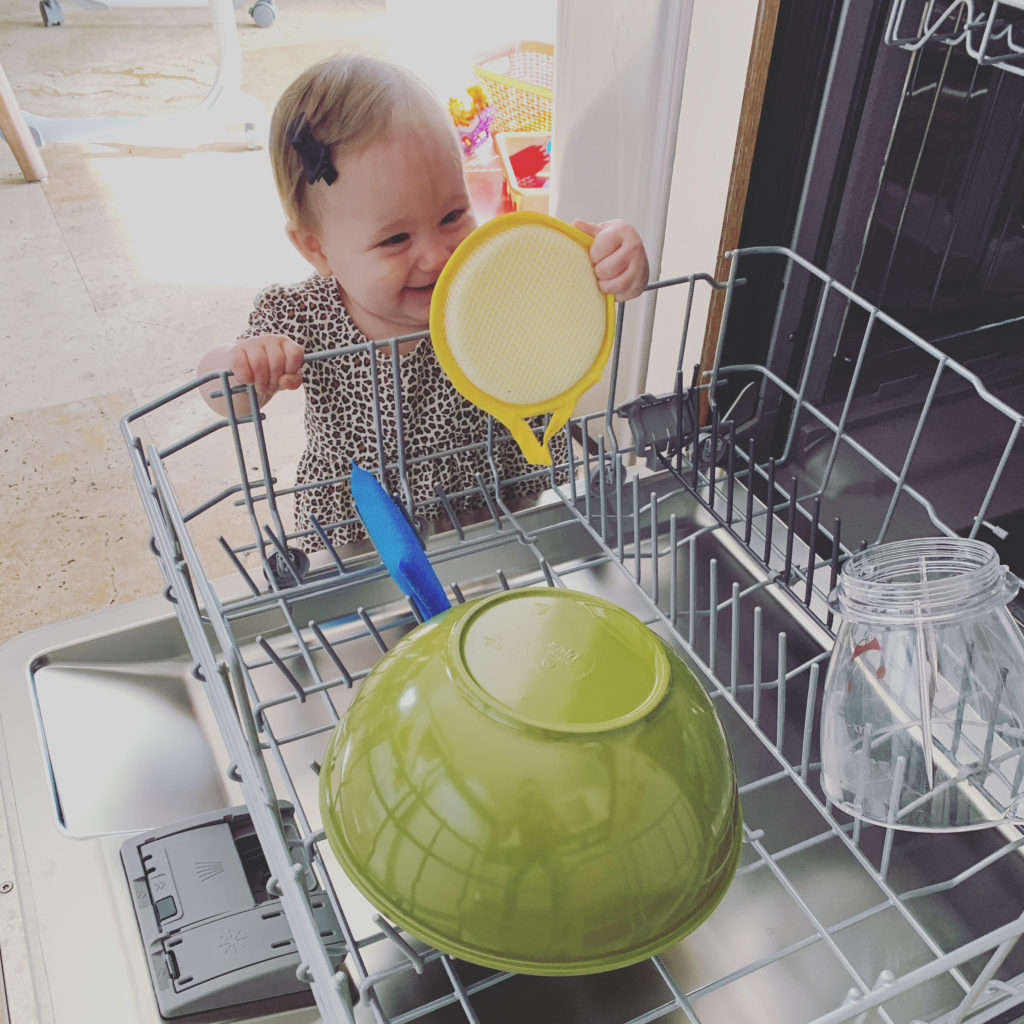 baby helping clean with sponge in dishwasher
