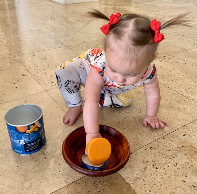 Baby reaching for bowl of lids