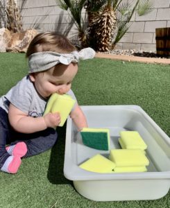Baby playing with wet and dry sponges outside