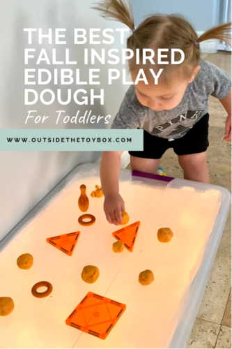 Toddler playing with orange play dough on light table