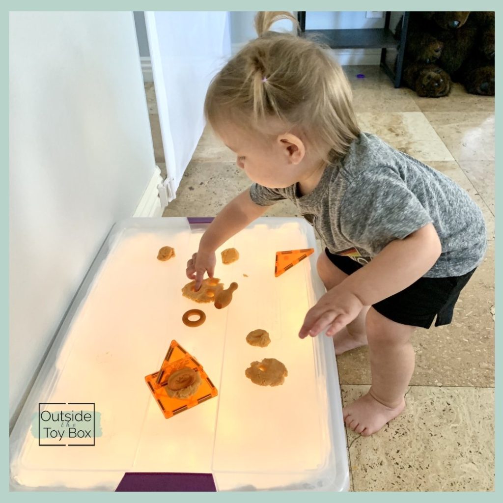 Toddler poking play dough on DIY Light table