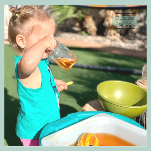 Toddler drinking orange water from water table