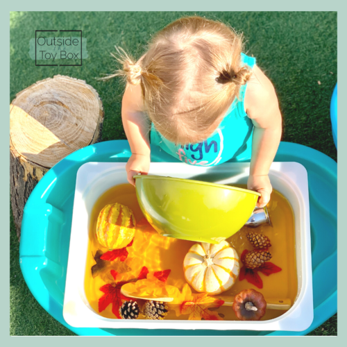 Toddler scooping fall themed water with bowl