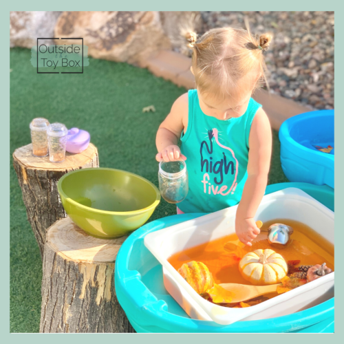 Toddler scooping water from fall themed sensory table