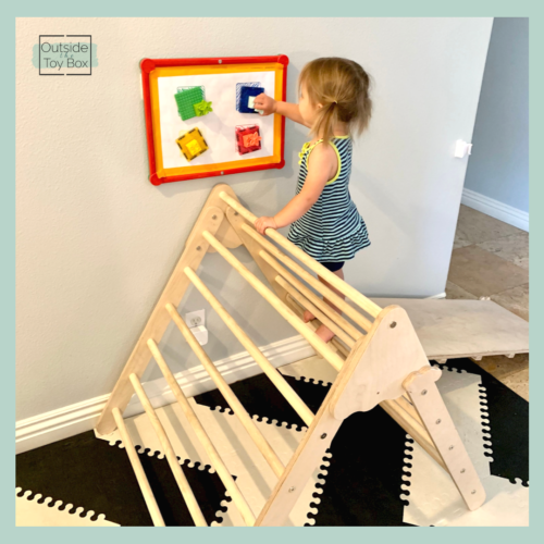 Toddler putting MAGBRIX on magnetic puzzle at the top of Pikler triangle
