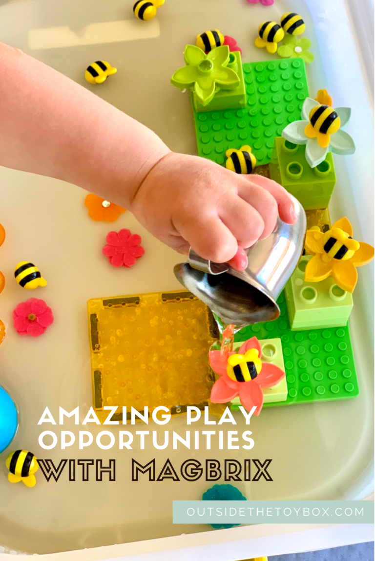 Toddler hand pouring water over MAGBRIX and DUPLO flowers