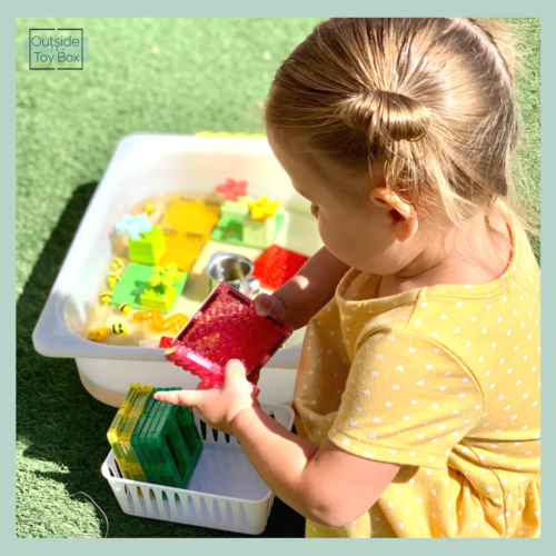 toddler outside putting MAGBRIX in water bin