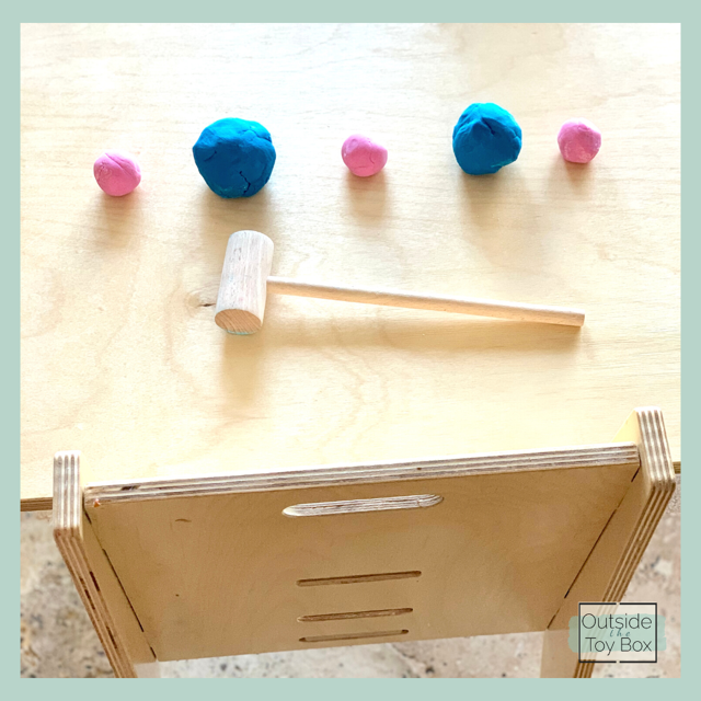 Blue and pink balls of play dough with wooden hammer