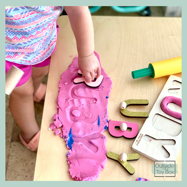 Toddler matching letter to letters imprinted in play dough