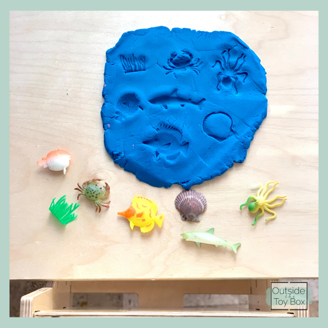 Sea animals imprinted in play dough with matching toys on table