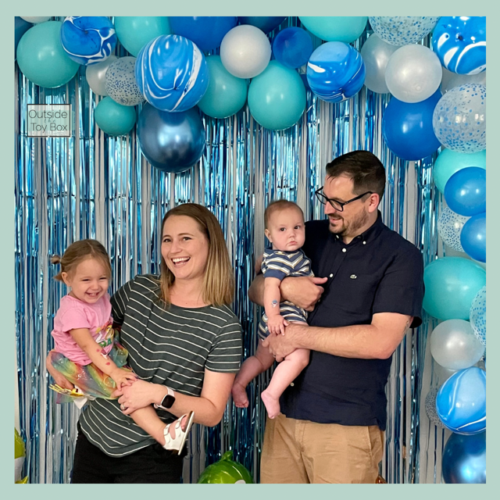 family photo next to feature wall and balloon garland
