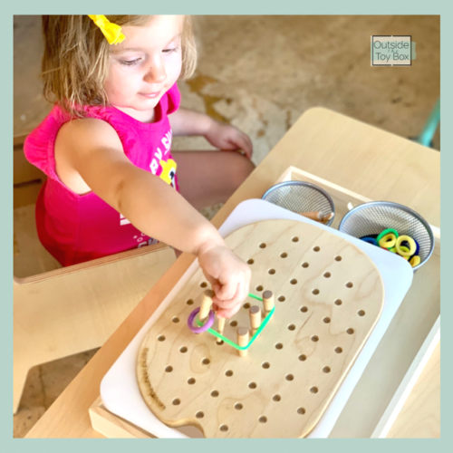 toddler playing with peg board