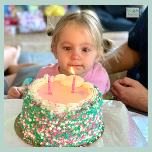toddler blowing out candles on cake