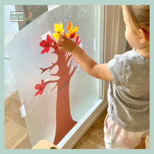 toddler matching and sticking letter leaf to a tree with contact paper